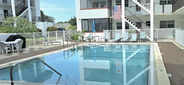 community pool with stairway, fence, and a patio area