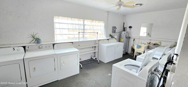 clothes washing area with washing machine and dryer, healthy amount of natural light, and water heater