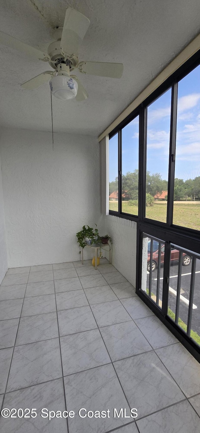 unfurnished sunroom featuring ceiling fan