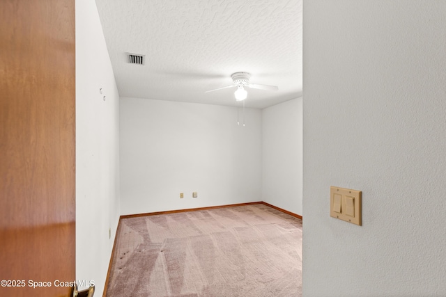 empty room featuring a ceiling fan, carpet floors, a textured ceiling, visible vents, and baseboards
