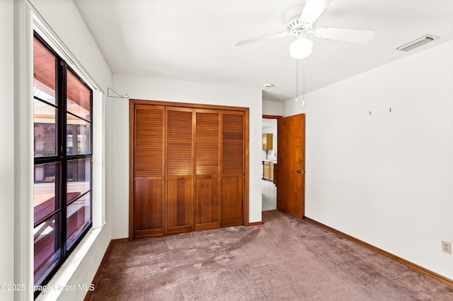 unfurnished bedroom with carpet flooring, a ceiling fan, a closet, visible vents, and baseboards