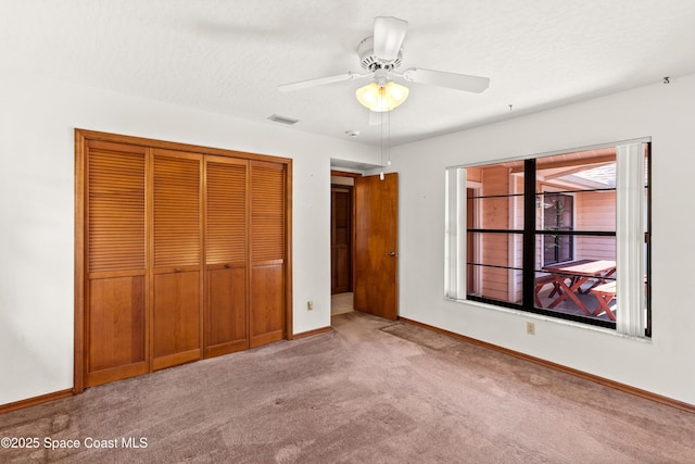 unfurnished bedroom featuring a closet, baseboards, ceiling fan, visible vents, and carpet floors