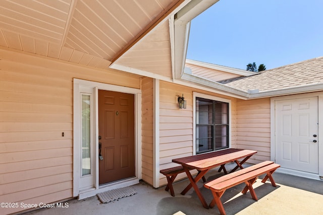 doorway to property with outdoor dining area and roof with shingles