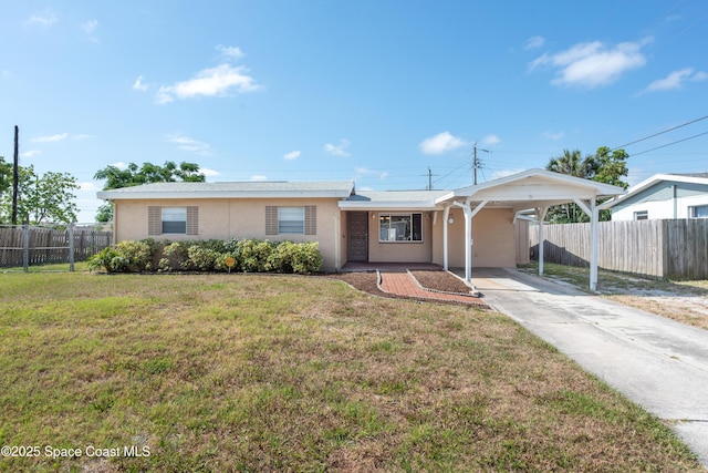 ranch-style house with fence, a front lawn, stucco siding, a carport, and driveway
