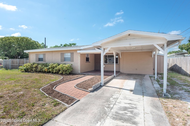 single story home with concrete driveway, fence, a front yard, and an attached carport