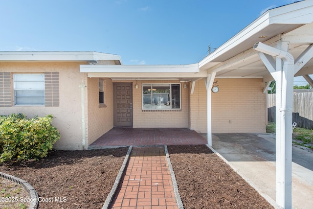 doorway to property featuring brick siding and fence