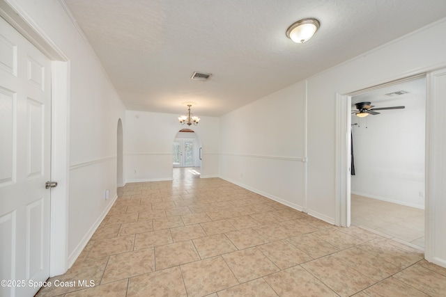 spare room with arched walkways, a textured ceiling, light tile patterned flooring, and visible vents
