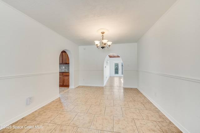 empty room with an inviting chandelier, arched walkways, and light tile patterned floors