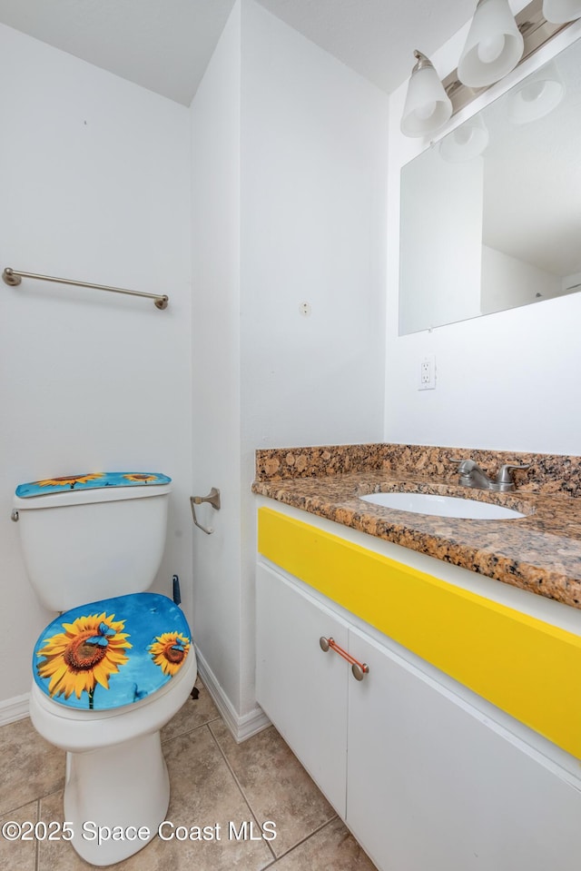 half bath with toilet, baseboards, tile patterned flooring, and vanity