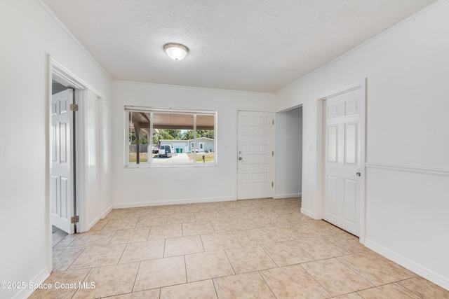spare room featuring crown molding, a textured ceiling, and light tile patterned floors