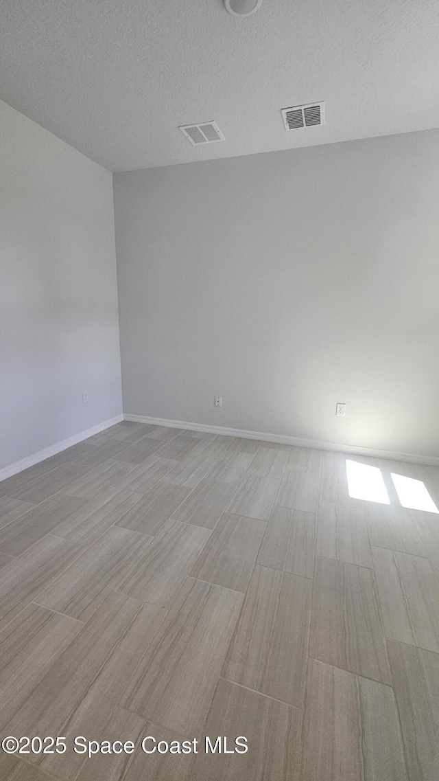 unfurnished room with visible vents, baseboards, and light wood-type flooring
