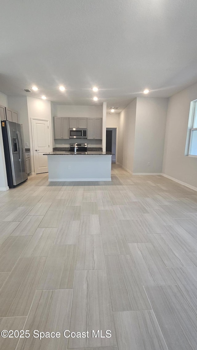 kitchen featuring gray cabinets, dark countertops, appliances with stainless steel finishes, open floor plan, and recessed lighting