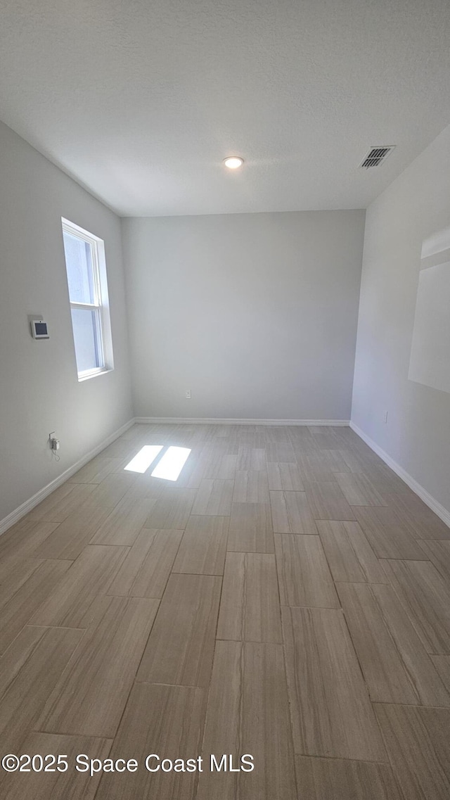 empty room with baseboards, recessed lighting, wood finished floors, and visible vents