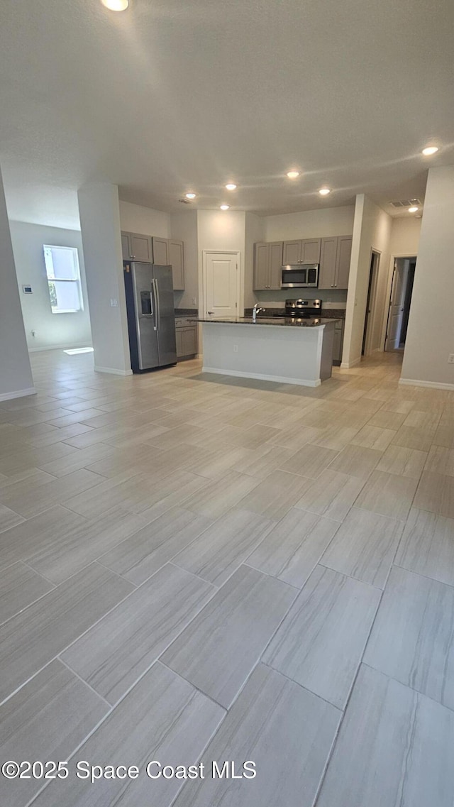 kitchen featuring dark countertops, stainless steel appliances, open floor plan, recessed lighting, and gray cabinetry