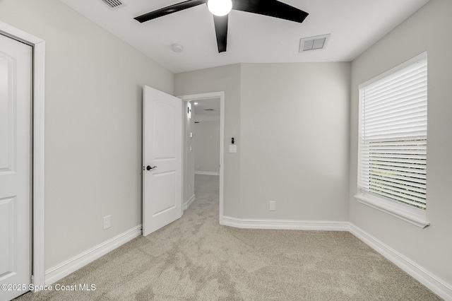 unfurnished bedroom featuring multiple windows, a ceiling fan, visible vents, carpet floors, and baseboards