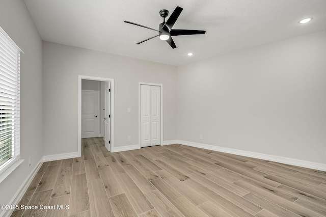 unfurnished bedroom featuring baseboards, light wood-style flooring, ceiling fan, and a closet