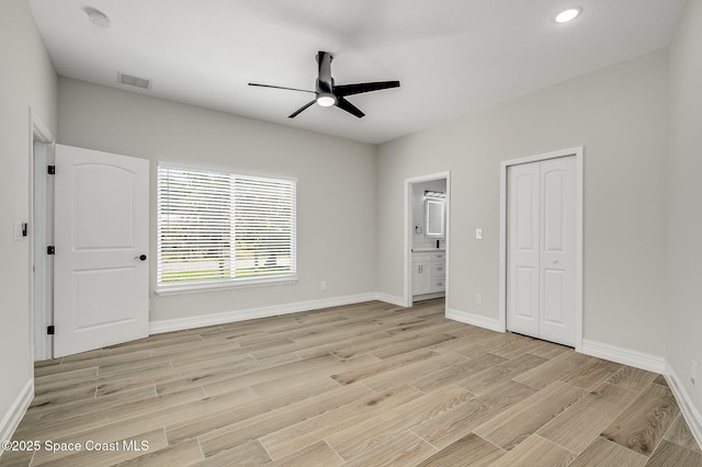 unfurnished bedroom featuring ceiling fan, visible vents, baseboards, light wood finished floors, and connected bathroom