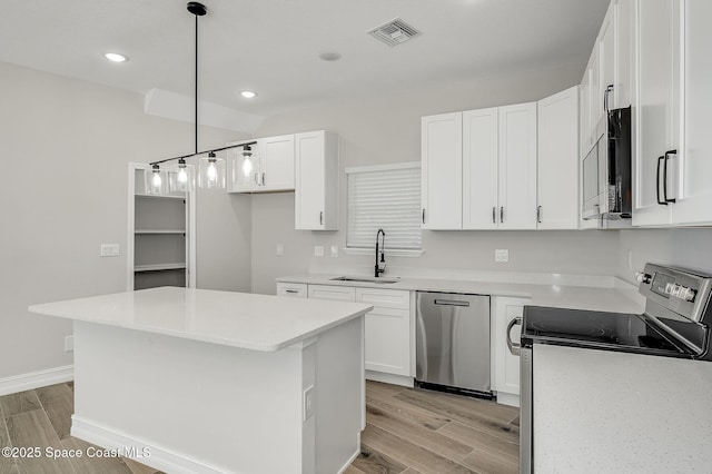 kitchen featuring stainless steel appliances, visible vents, a sink, and light wood-type flooring