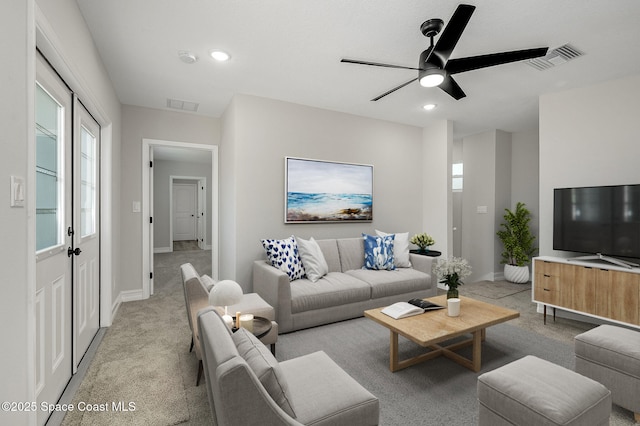living area featuring visible vents, baseboards, ceiling fan, and light carpet