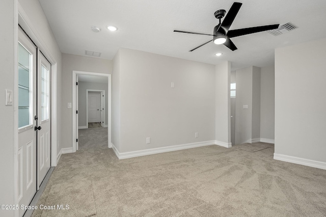 unfurnished room with visible vents, a ceiling fan, baseboards, and light carpet