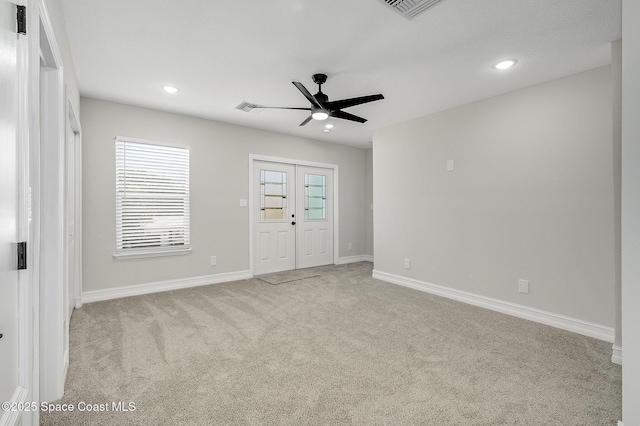 interior space featuring visible vents, baseboards, ceiling fan, and light carpet