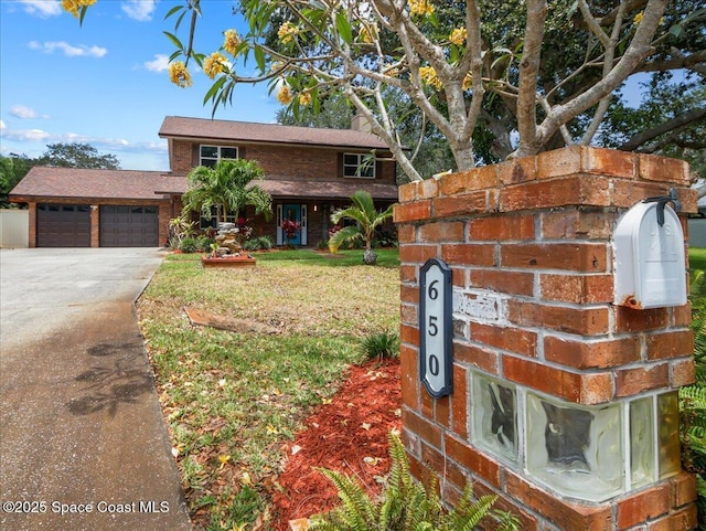 view of front facade featuring a garage, a front lawn, a chimney, brick siding, and driveway
