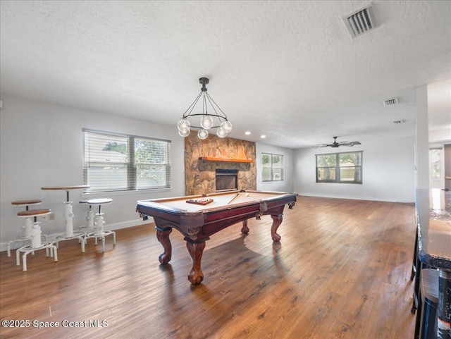 recreation room featuring visible vents, baseboards, a textured ceiling, and wood finished floors