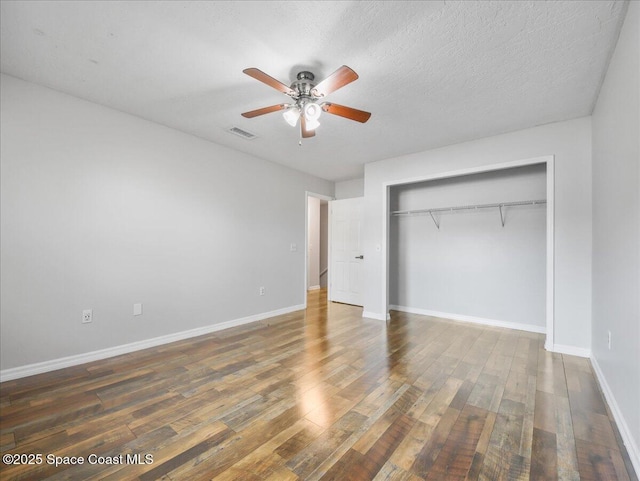 unfurnished bedroom with visible vents, baseboards, wood finished floors, and a closet