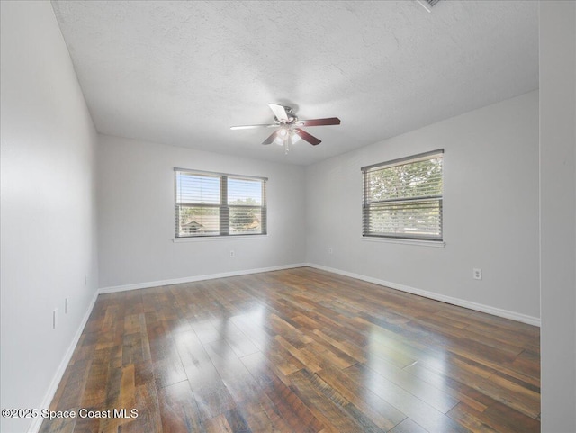 empty room featuring a healthy amount of sunlight, a ceiling fan, and hardwood / wood-style flooring