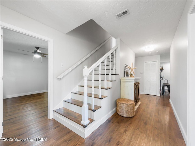 stairs with baseboards, ceiling fan, wood finished floors, and visible vents