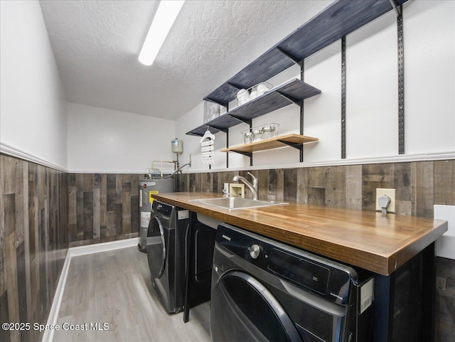 laundry area featuring light wood-style floors, a sink, washer / dryer, and electric water heater