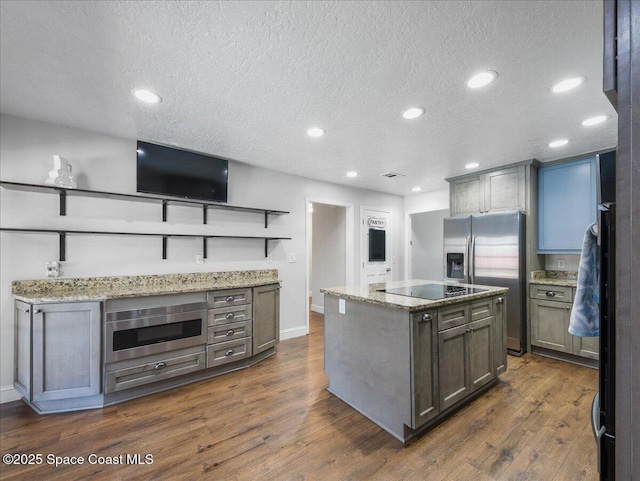 kitchen featuring black electric stovetop, stainless steel fridge with ice dispenser, a textured ceiling, a center island, and recessed lighting