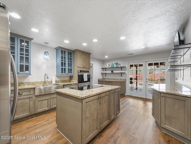 kitchen featuring a center island, a textured ceiling, french doors, a sink, and stainless steel appliances