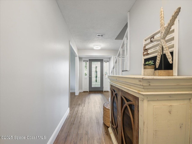 laundry room featuring visible vents, a textured ceiling, baseboards, and wood finished floors