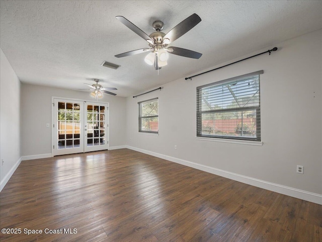 empty room with dark wood-style flooring, ceiling fan, visible vents, and baseboards