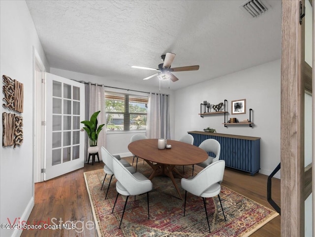 dining room featuring a ceiling fan, a textured ceiling, visible vents, wood finished floors, and baseboards