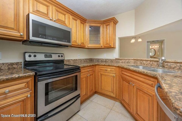 7667 N Wickham Rd Unit 903, Melbourne, FL 32940 - kitchen with appliances with stainless steel finishes, brown cabinets, light tile patterned floors, dark stone countertops, and glass insert cabinets