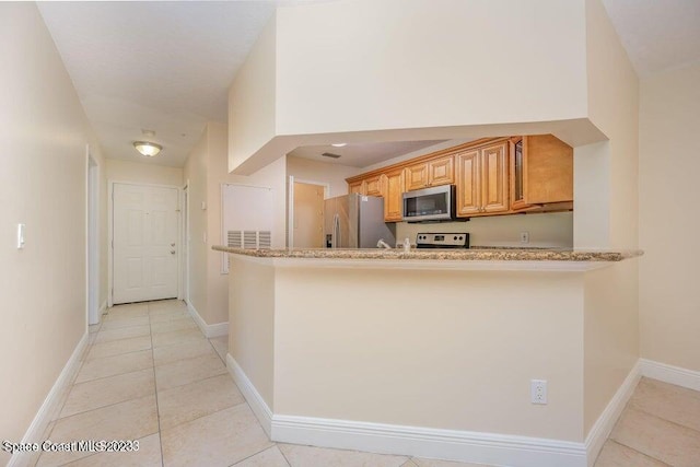7667 N Wickham Rd Unit 903, Melbourne, FL 32940 - kitchen with stainless steel appliances, light tile patterned floors, a peninsula, and light stone counters