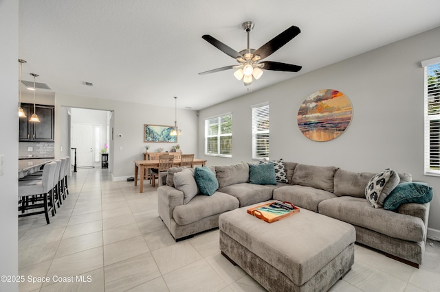 living room with baseboards, ceiling fan, light tile patterned flooring, and a wealth of natural light