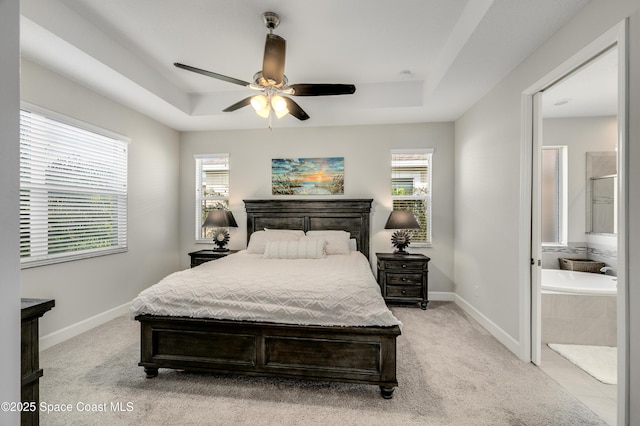 bedroom featuring baseboards, a tray ceiling, multiple windows, and light colored carpet