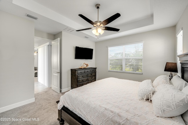 bedroom with a tray ceiling, baseboards, light colored carpet, and visible vents