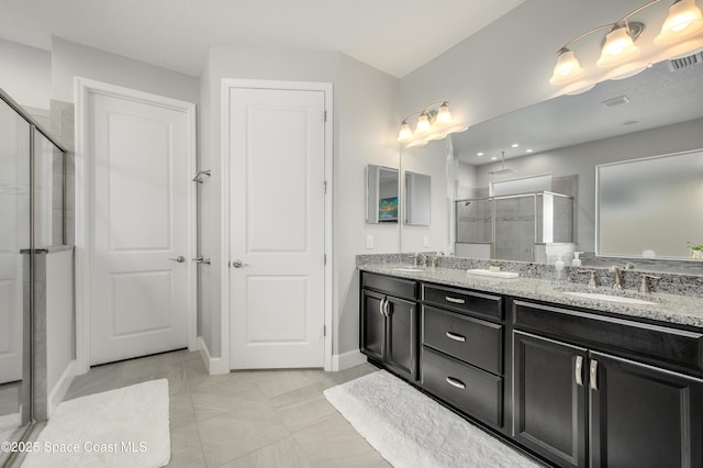 full bathroom with double vanity, baseboards, a shower stall, and a sink