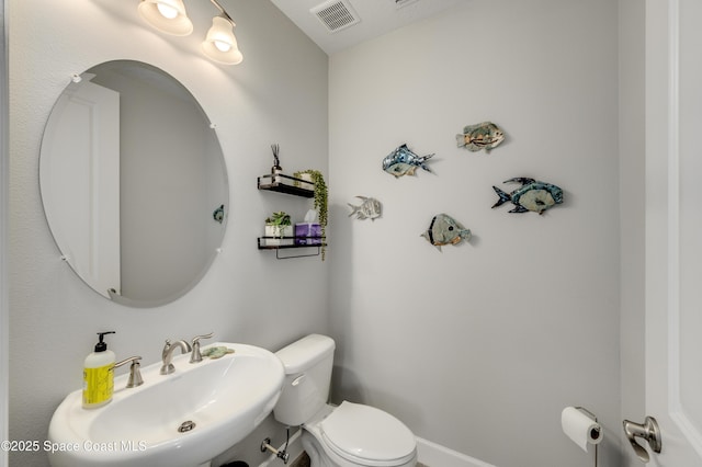 bathroom with a sink, toilet, and visible vents