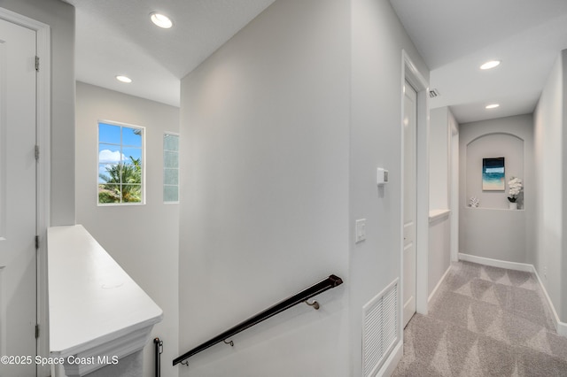 hallway with light carpet, recessed lighting, baseboards, an upstairs landing, and visible vents