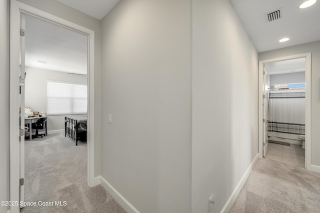 hall featuring baseboards, visible vents, recessed lighting, and light colored carpet
