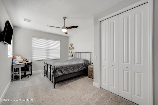 carpeted bedroom with a textured ceiling, baseboards, visible vents, and multiple windows