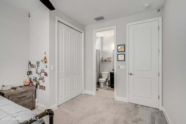 bedroom featuring carpet flooring, ensuite bath, baseboards, visible vents, and a closet