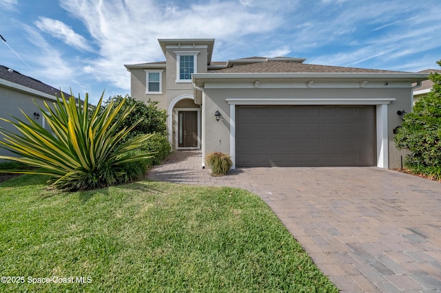 mediterranean / spanish-style home featuring decorative driveway, a garage, a front yard, and stucco siding