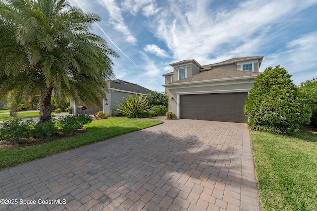 view of front of house featuring decorative driveway, an attached garage, a front lawn, and stucco siding