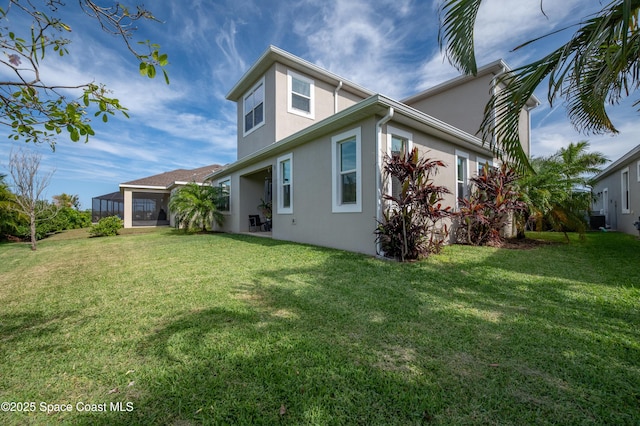 back of property featuring a lawn, stucco siding, and a sunroom
